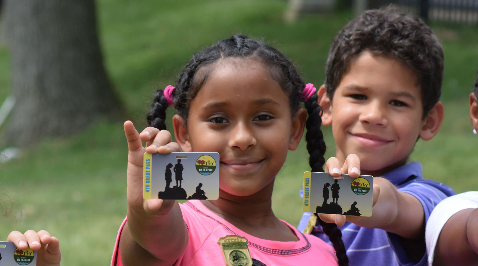 Two students hold up their Every Kid in a Park passes